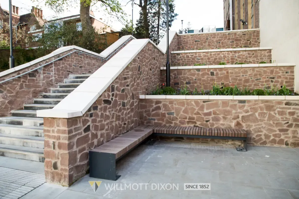 Stone outdoor staircase with white railings and brick retaining walls on a landscaped slope