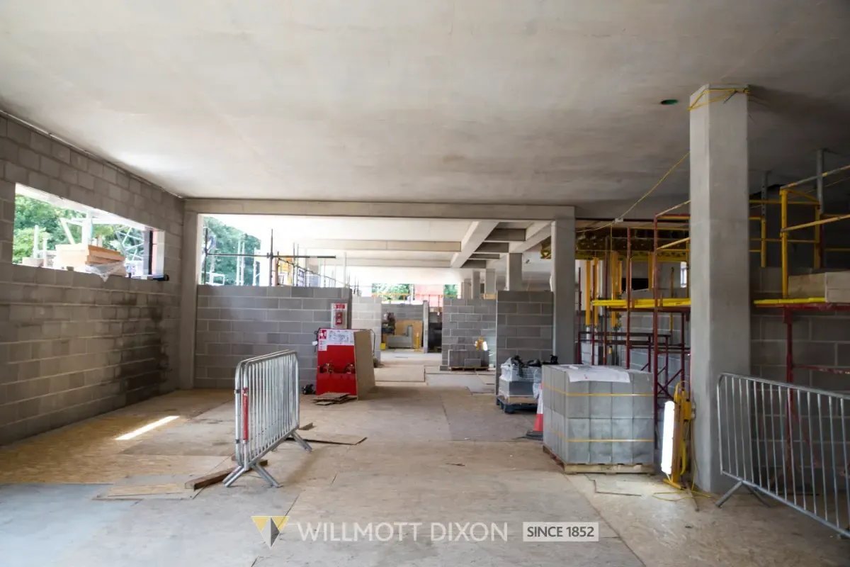 Interior of an unfinished building with concrete walls, scaffolding, and construction materials scattered around