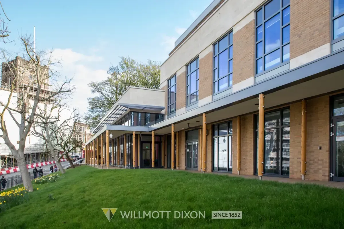 Modern brick-and-glass office building with covered walkway and green lawn