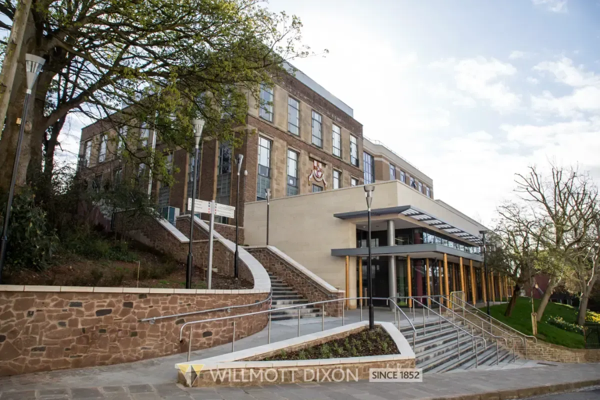 Modern brick campus building with stairs, trees, and a covered entrance