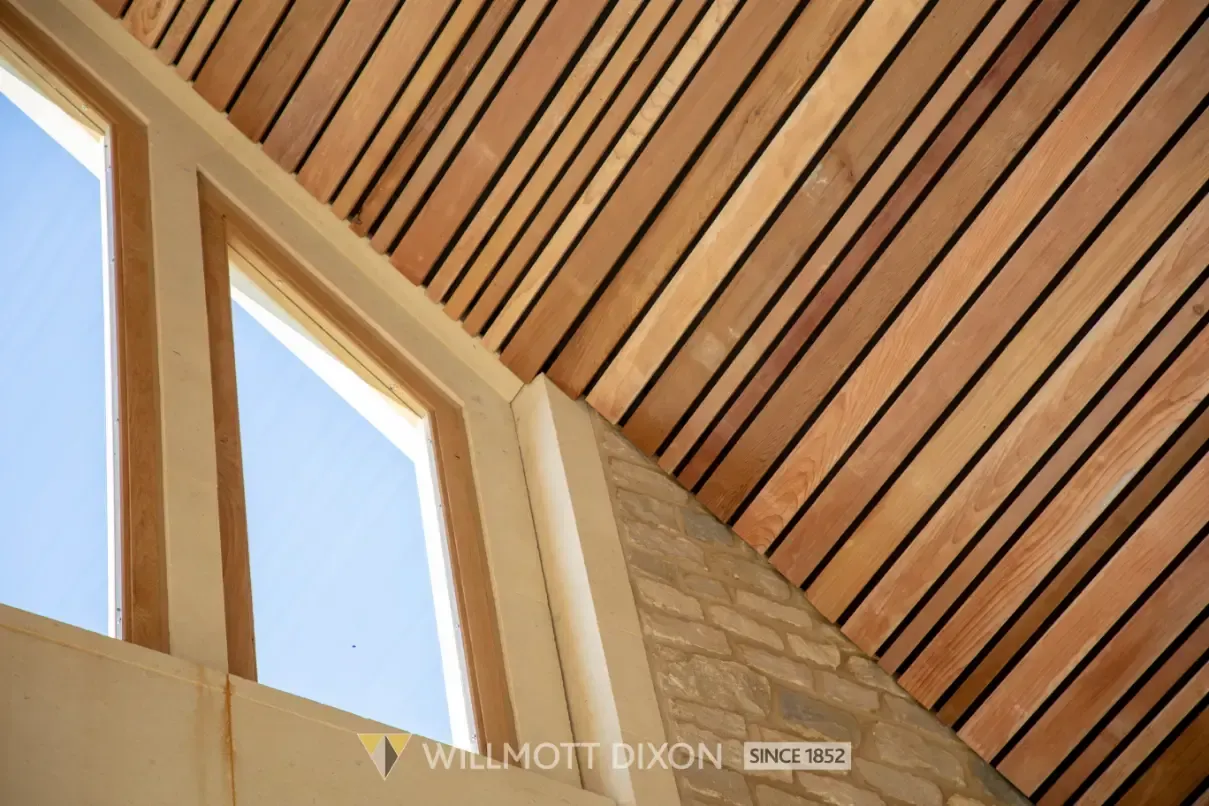 Wooden slatted ceiling with skylights and blue sky visible through angular window frames