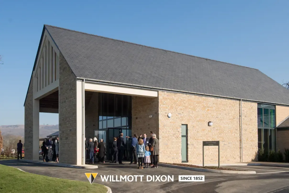 Modern brick and wood church building with people gathered outside under a gray roof
