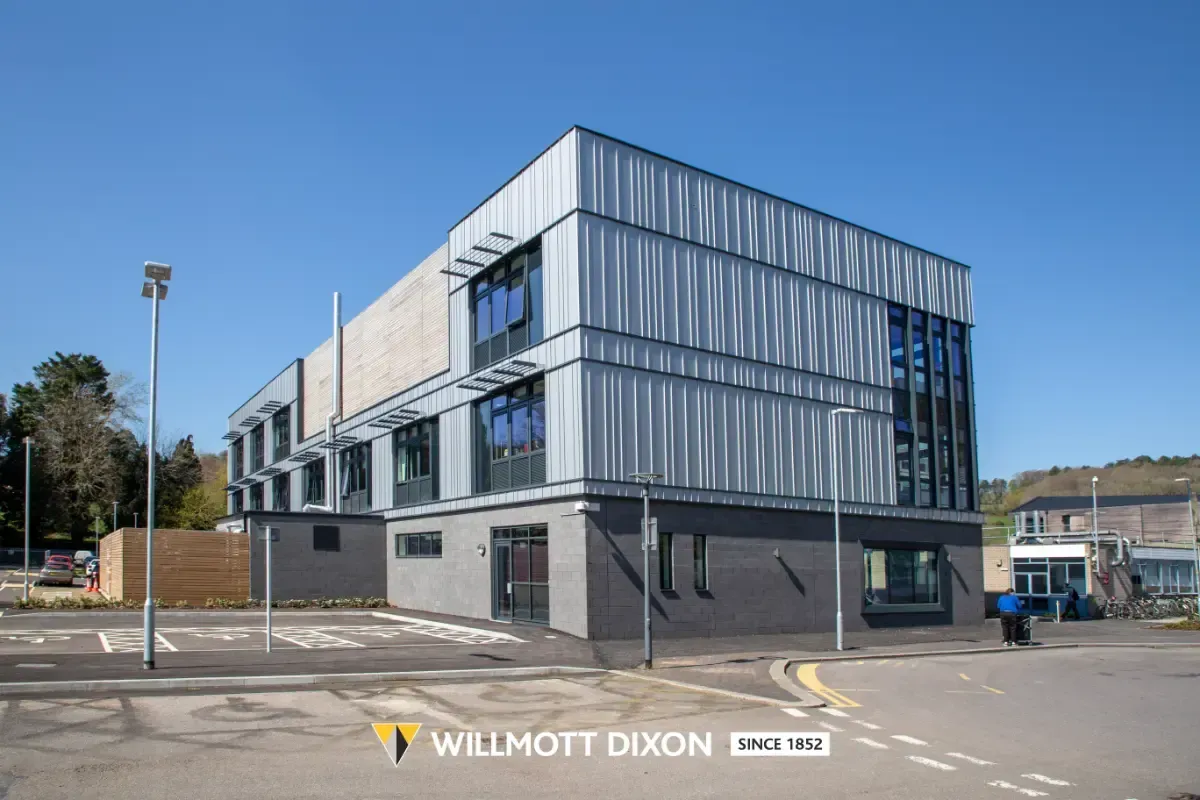Modern three-story office building with glass facade on a sunny street corner