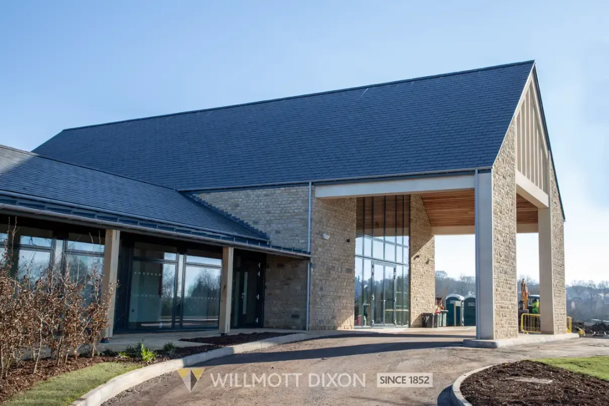 Modern brick-and-glass house with a dark blue roof and covered entryway