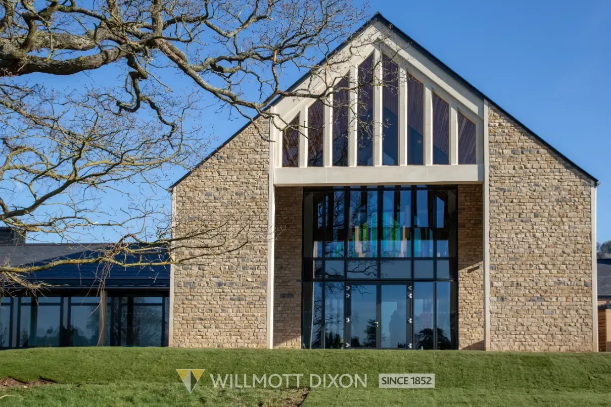 Stone building with a peaked roof, blue glass entrance, and “WILLIAM DIXON” sign in front