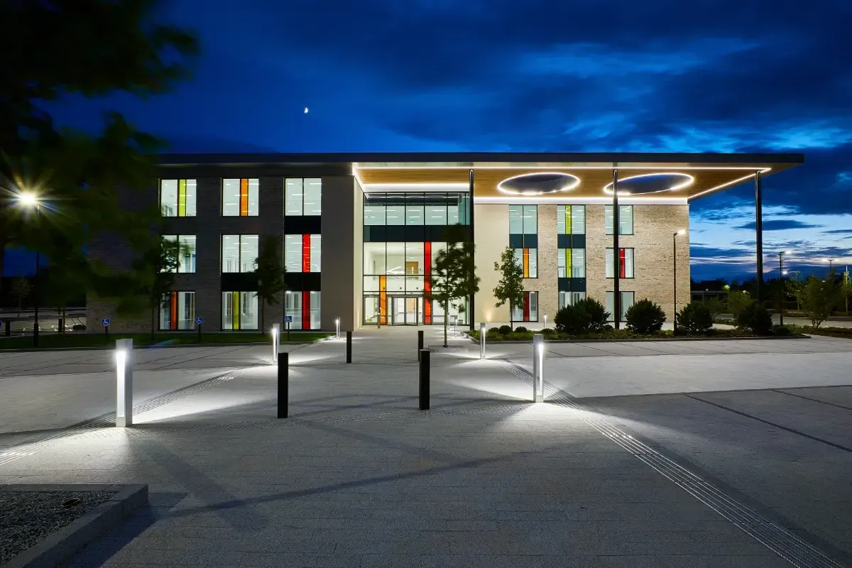 Modern building entrance at night with lit walkway and glass facade