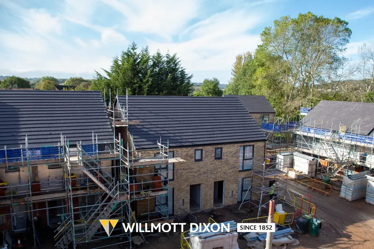 Roofing construction on a large house with scaffolding and workers under a blue sky
