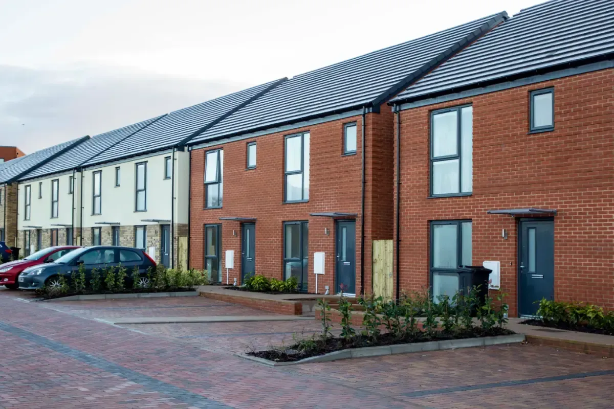 Row of modern brick townhouses with parked cars on a paved residential street