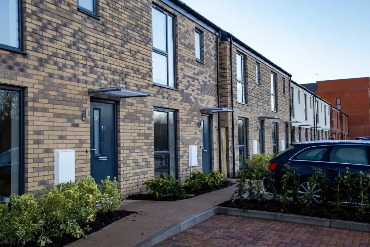 Row of modern brick townhouses with blue doors and a parked car in front