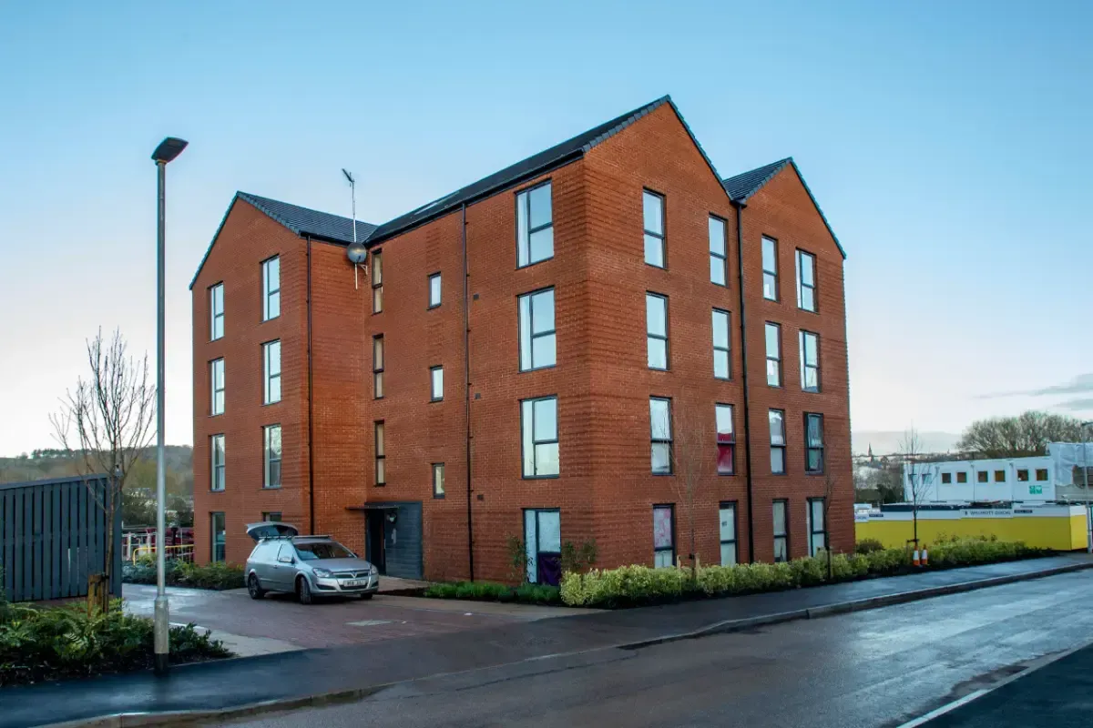Red brick apartment building with parked car on a wet street