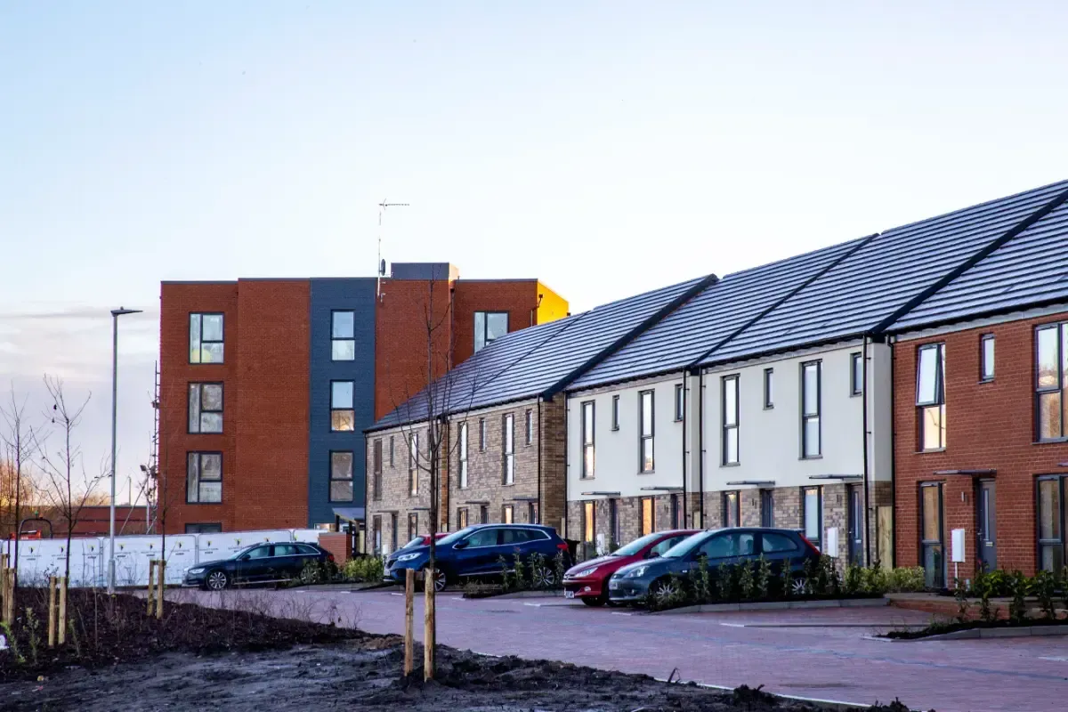 Row of modern townhouses with parked cars on a quiet street under a clear sky