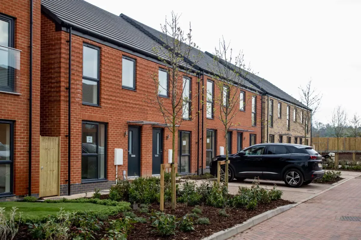 Row of modern brick townhouses with a parked black SUV and landscaped front walkway
