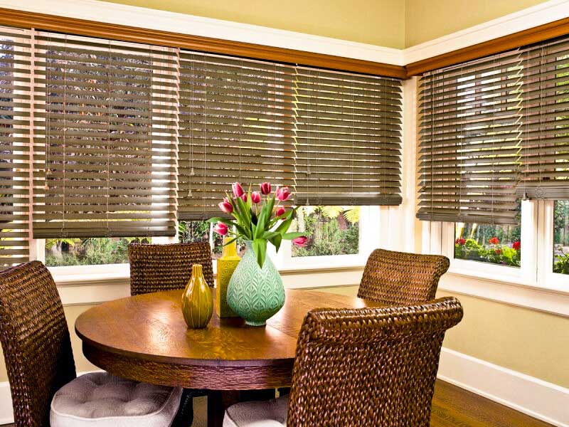 a dining room with wood and woven wood shades a table and chairs and a vase of flowers on the table Love is Blinds Missouri 