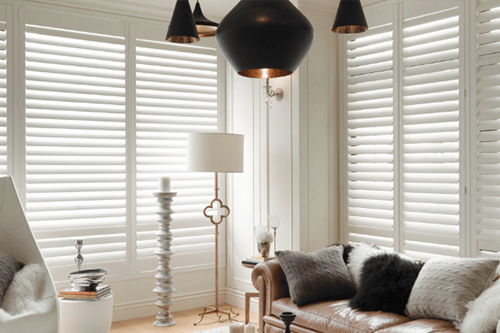a living room with a couch , chair , lamp and white shutters Love is Blinds Missouri (314) 808-3440.