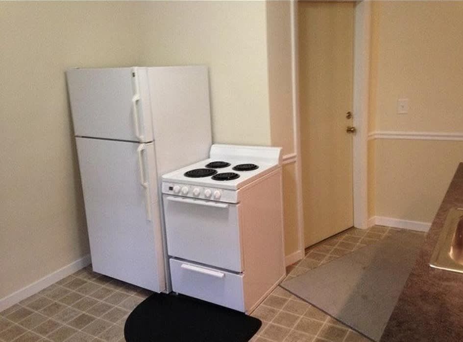 White refrigerator and stove in a kitchen, next to a door and tiled floor.
