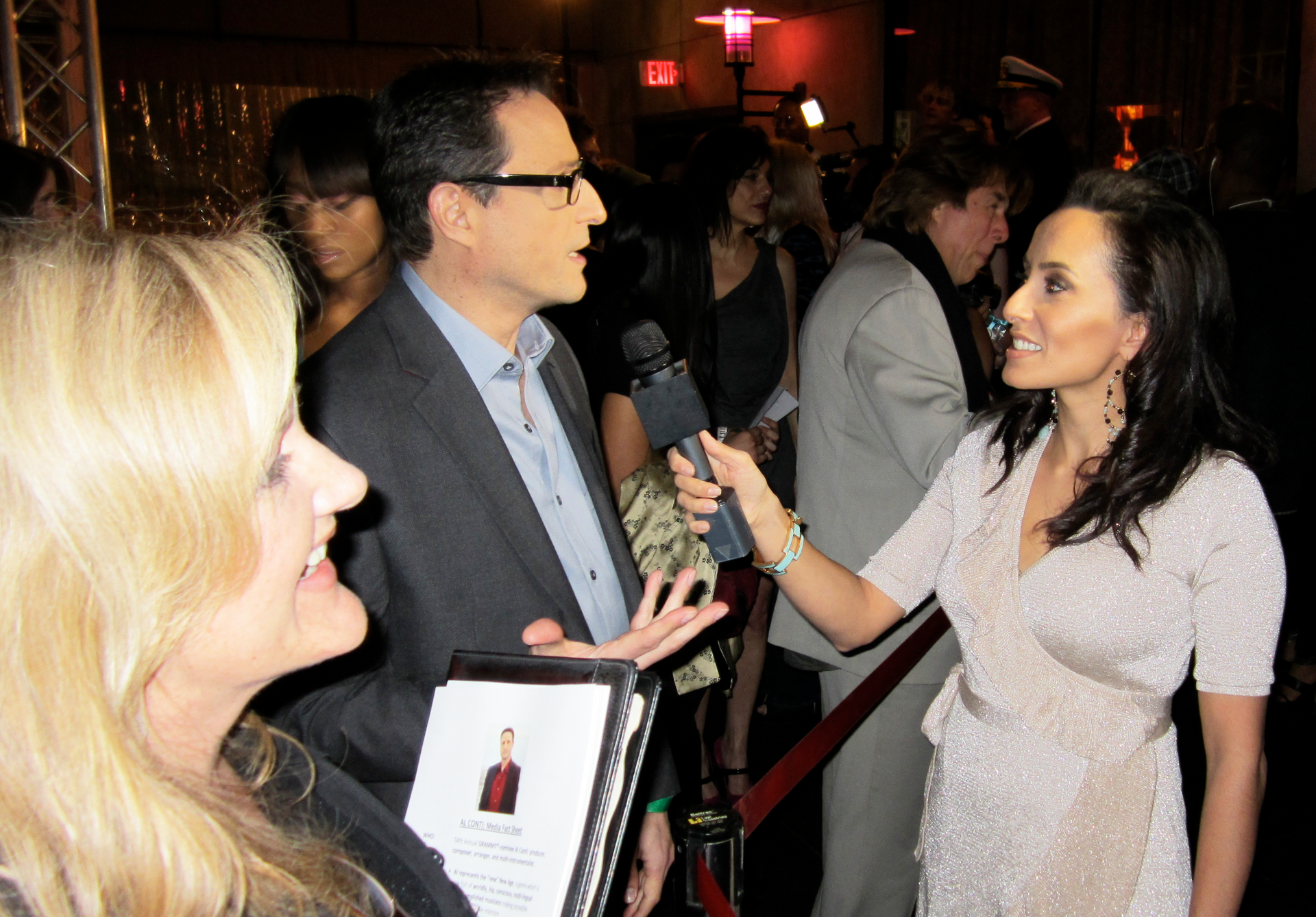 Reporter interviewing Al Conti at a red carpet event. Other people watch.