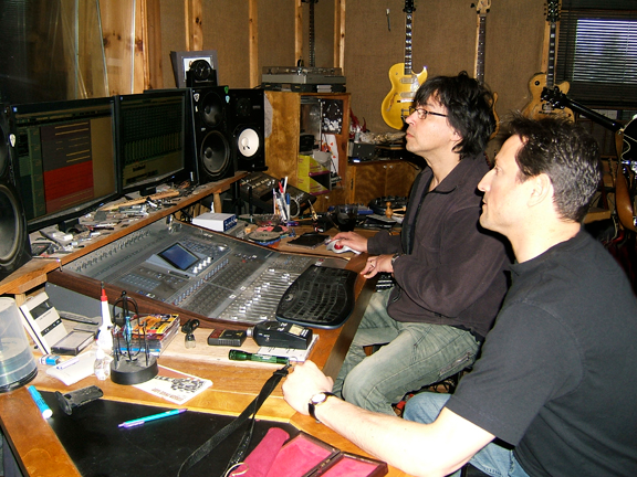 Al and André, recording engineer working at a mixing console in a recording studio, focused on screens.
