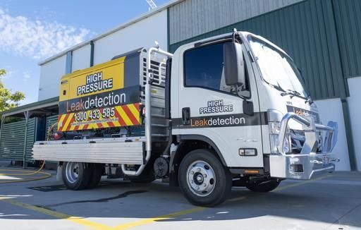 High-pressure leak detection truck parked outside a building, advertising its service.
