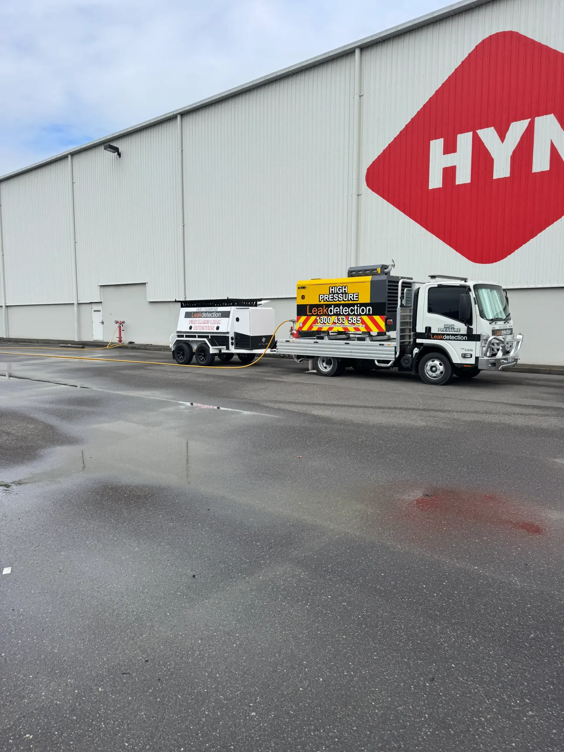 Truck with equipment trailer parked in front of large building with 