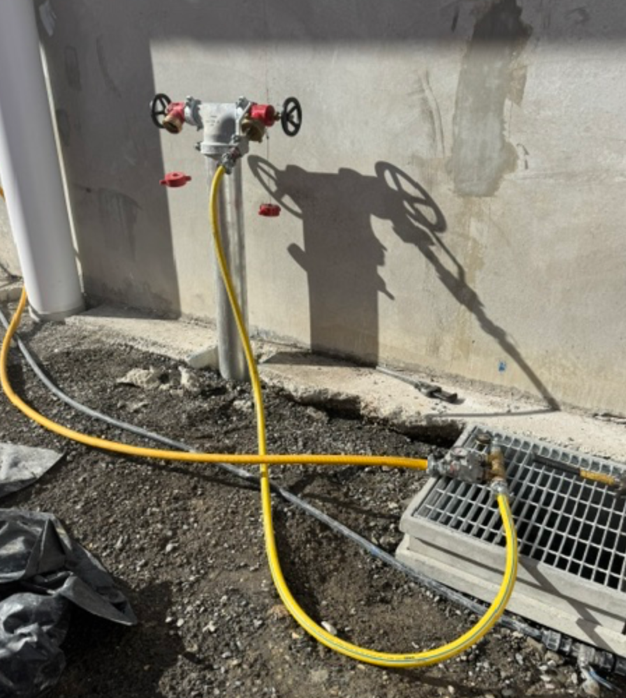 Fire Hydrant Booster With Yellow Hose Connected To Drain Grate — Commercial Leak Detection in Mudgeeraba, QLD