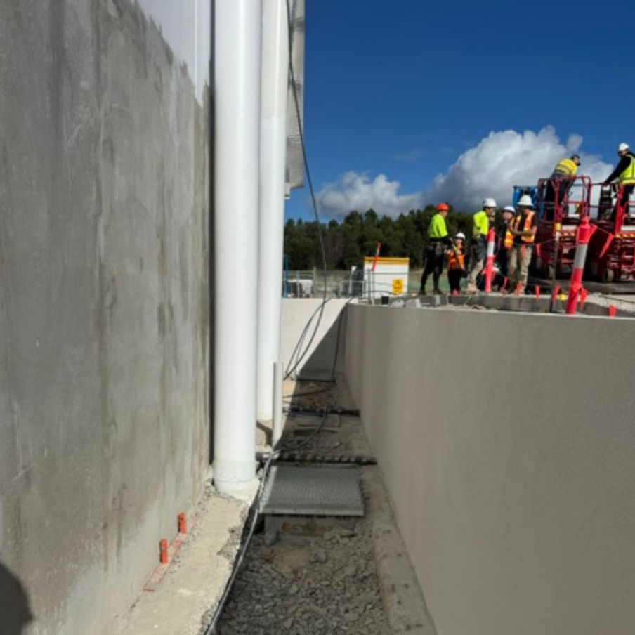 Workers Beside White Fire Main Pipes And Concrete Walls &mdash; Commercial Leak Detection in Mudgeeraba, QLD
