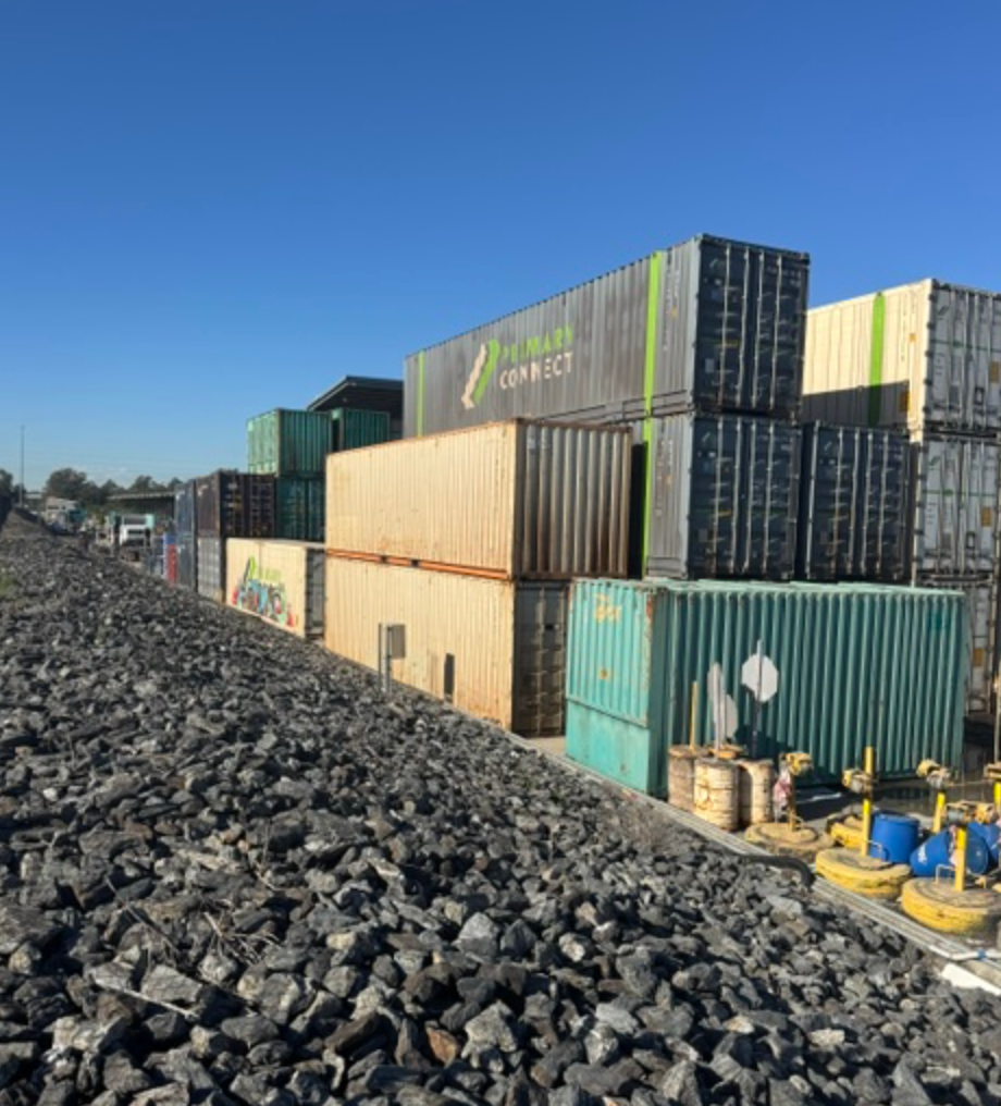 Stacked Shipping Containers Beside Rail Ballast Under Blue Sky — Commercial Leak Detection in Mudgeeraba, QLD