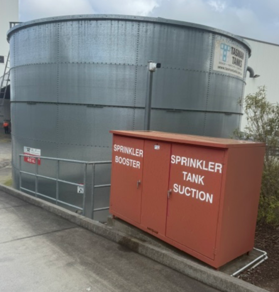 Red Sprinkler Booster Cabinet Beside Large Steel Water Tank &mdash; Commercial Leak Detection in Mudgeeraba, QLD