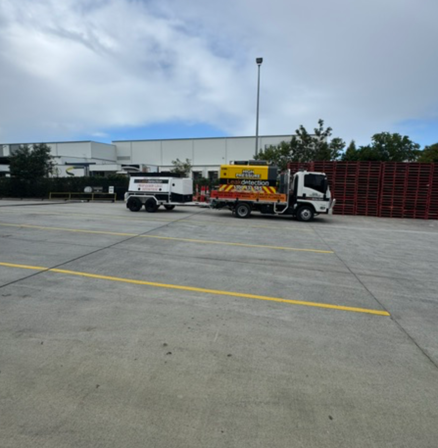 Leak Detection Truck And Trailer Parked Beside Red Pallet Stack &mdash; Commercial Leak Detection in Mudgeeraba, QLD