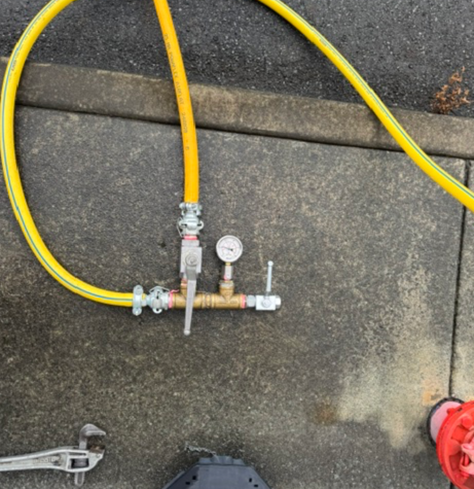 Yellow Hose With Brass Pressure Gauge Fitting On Concrete &mdash; Commercial Leak Detection in Mudgeeraba, QLD