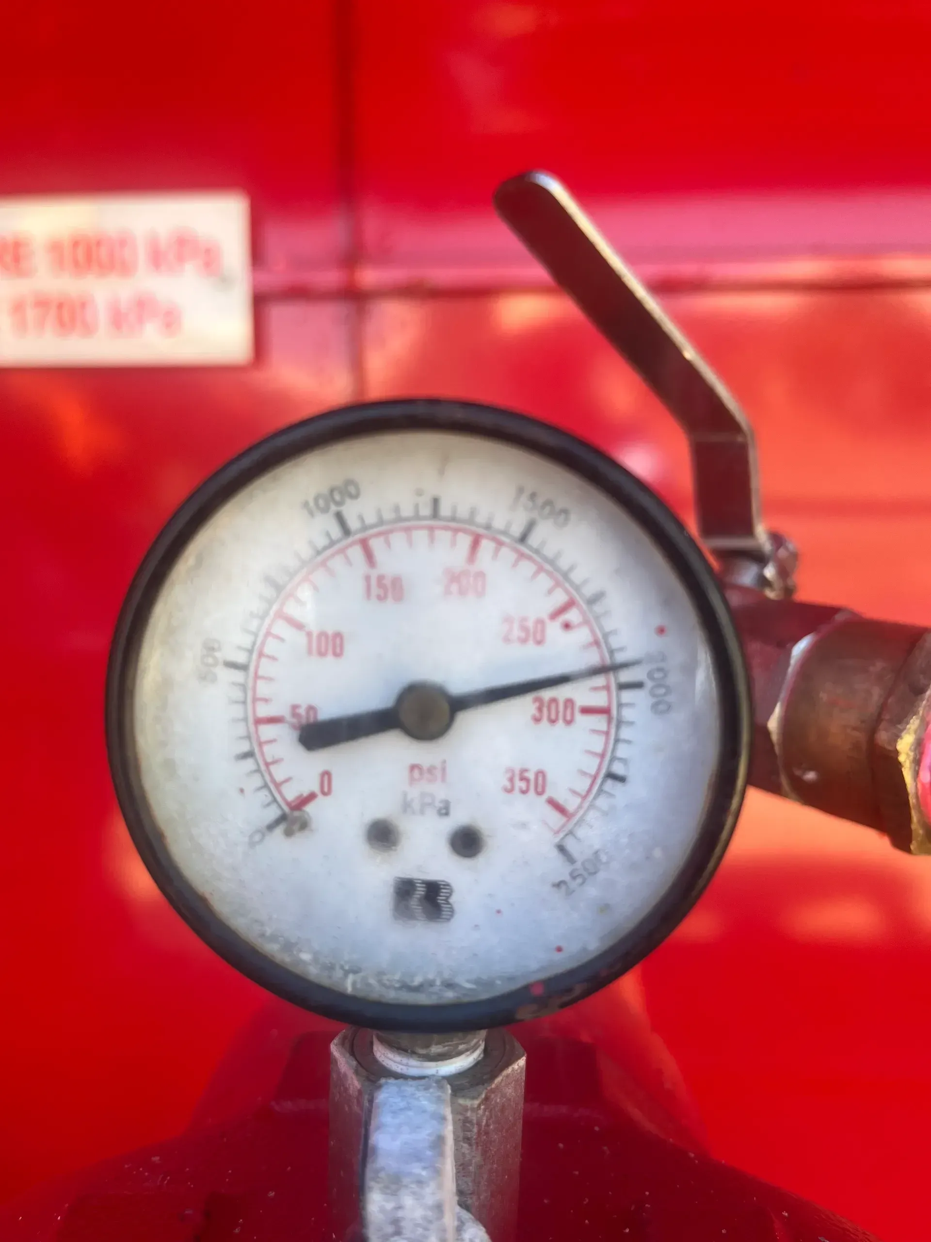 Pressure gauge with a needle pointing to about 280, mounted on red equipment. — Commercial Leak Detection