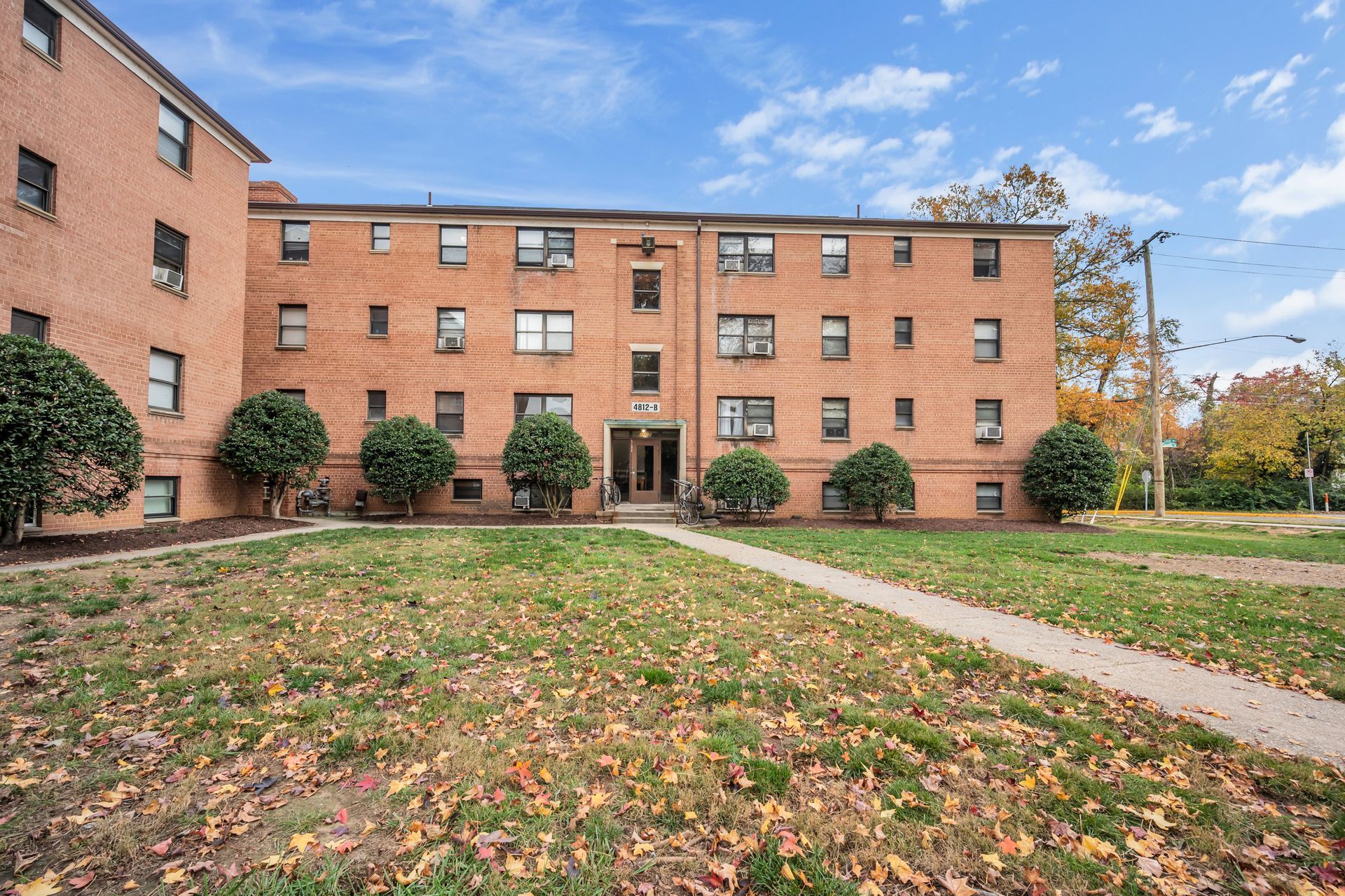 A large brick apartment building with a lush green lawn in front of it.