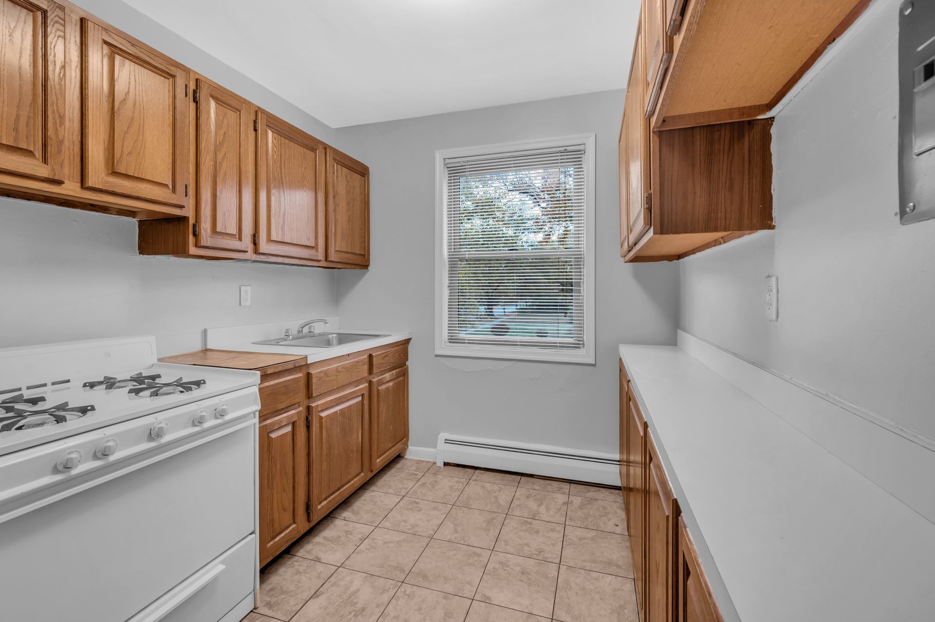 An empty kitchen with wooden cabinets and a white stove.