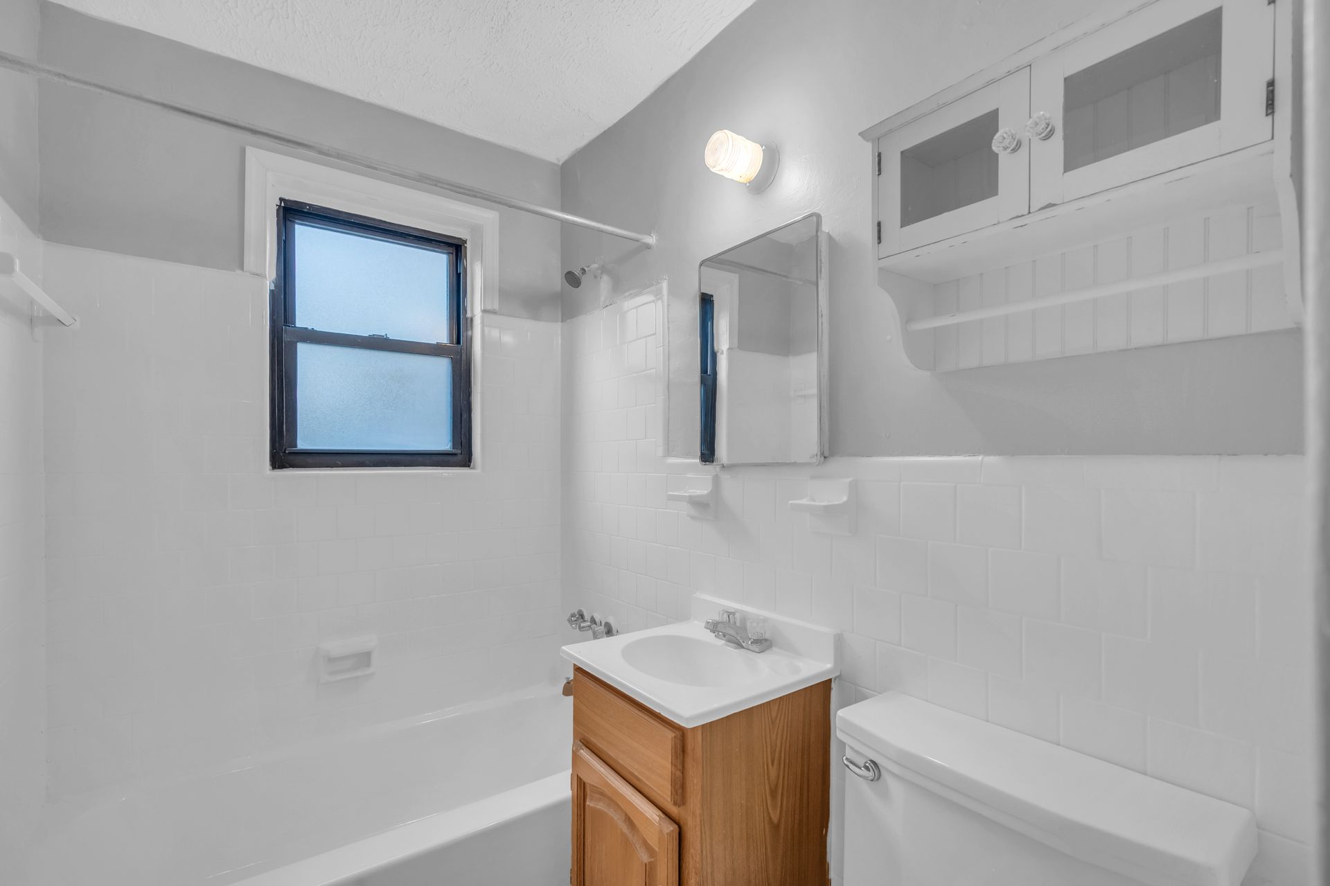 A bathroom with a sink, toilet, bathtub and window.