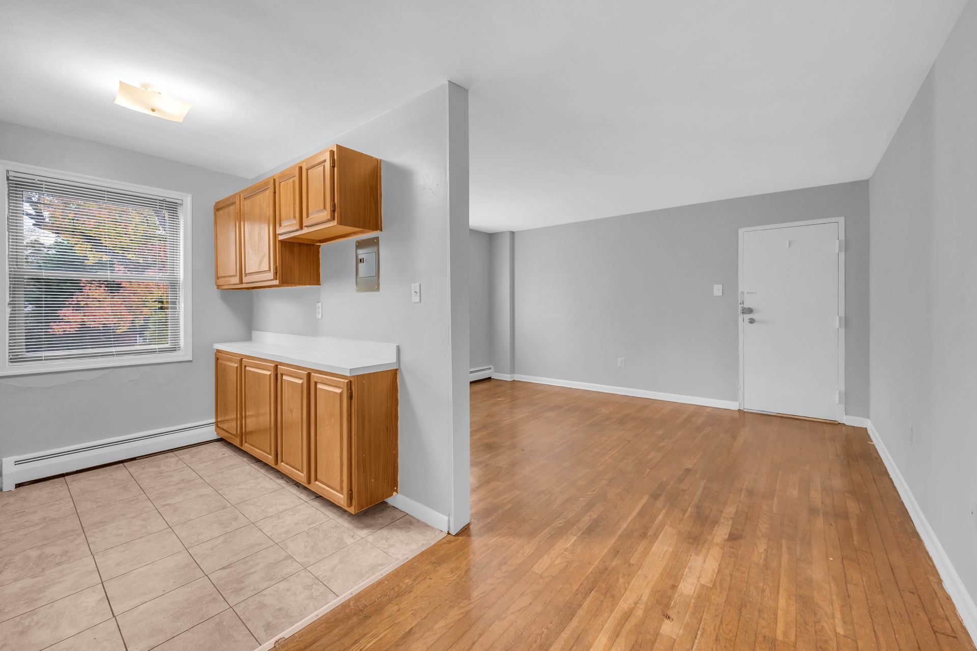 An empty kitchen with wooden cabinets and hardwood floors.