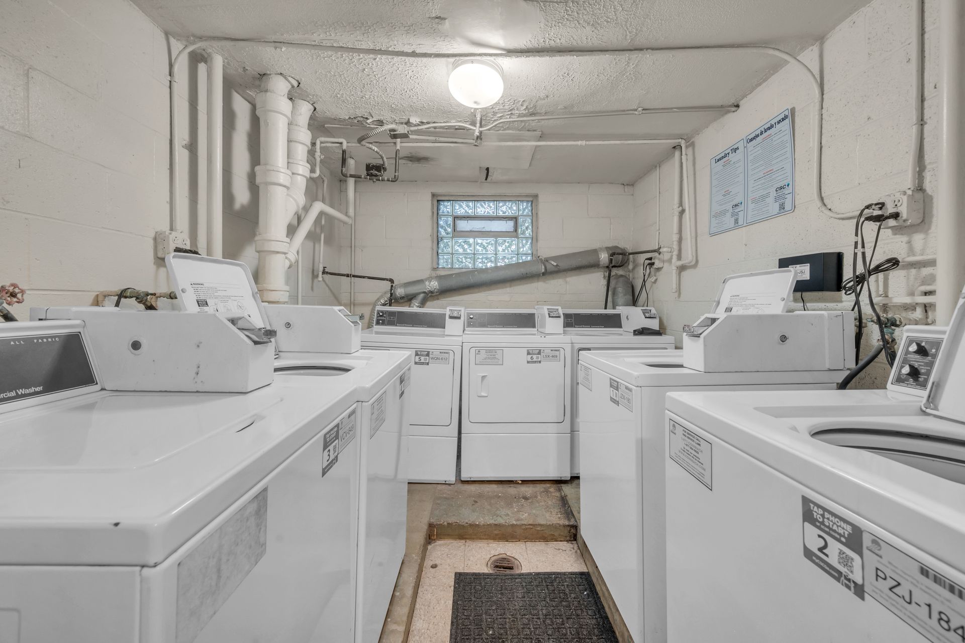 A laundromat filled with lots of white washers and dryers.