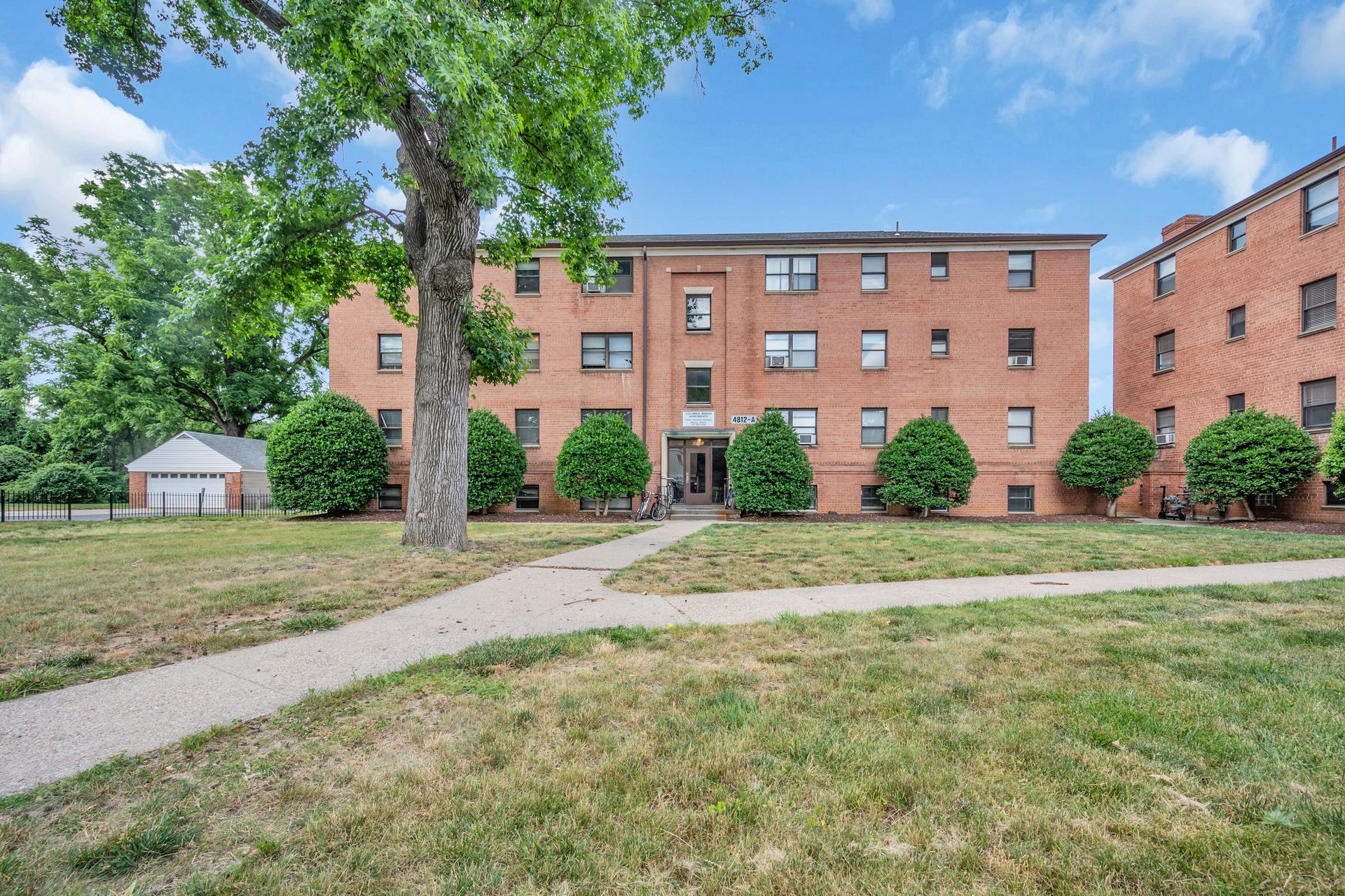A large brick apartment building with a tree in front of it.