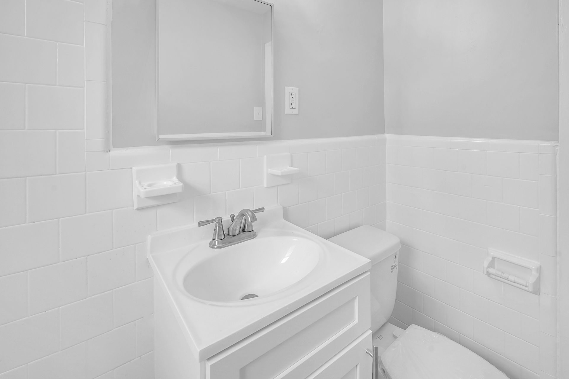 A bathroom with a sink, toilet, and mirror.