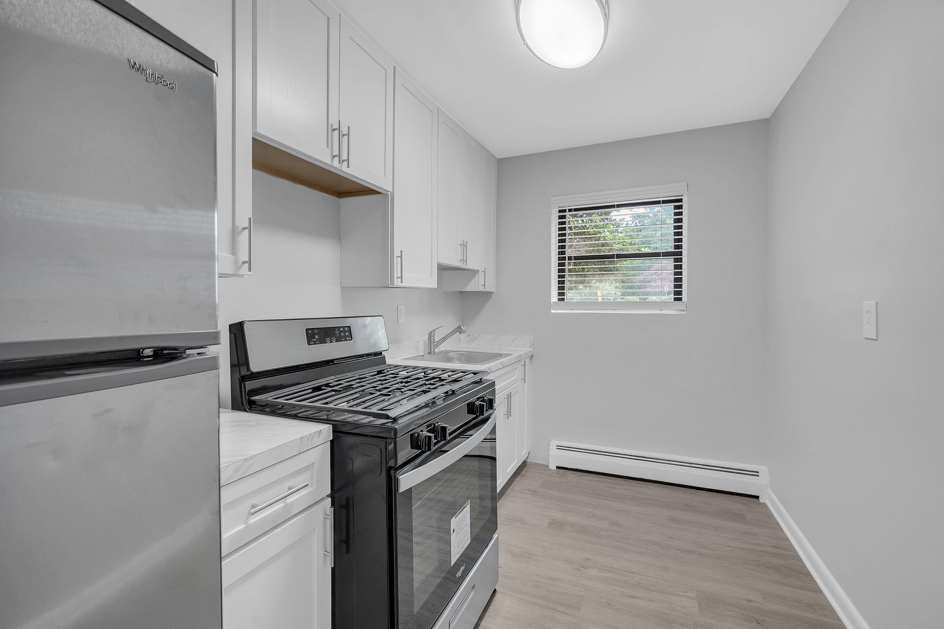 A kitchen with a stove, refrigerator, dishwasher ,and a window.