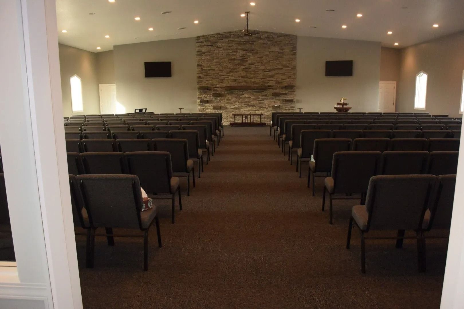 Empty chapel with rows of chairs facing a stone altar and recessed ceiling lights