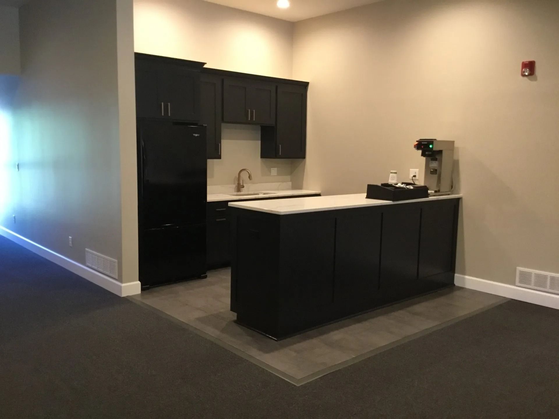 Modern kitchen with black cabinets, white countertops, and a central island in a beige room