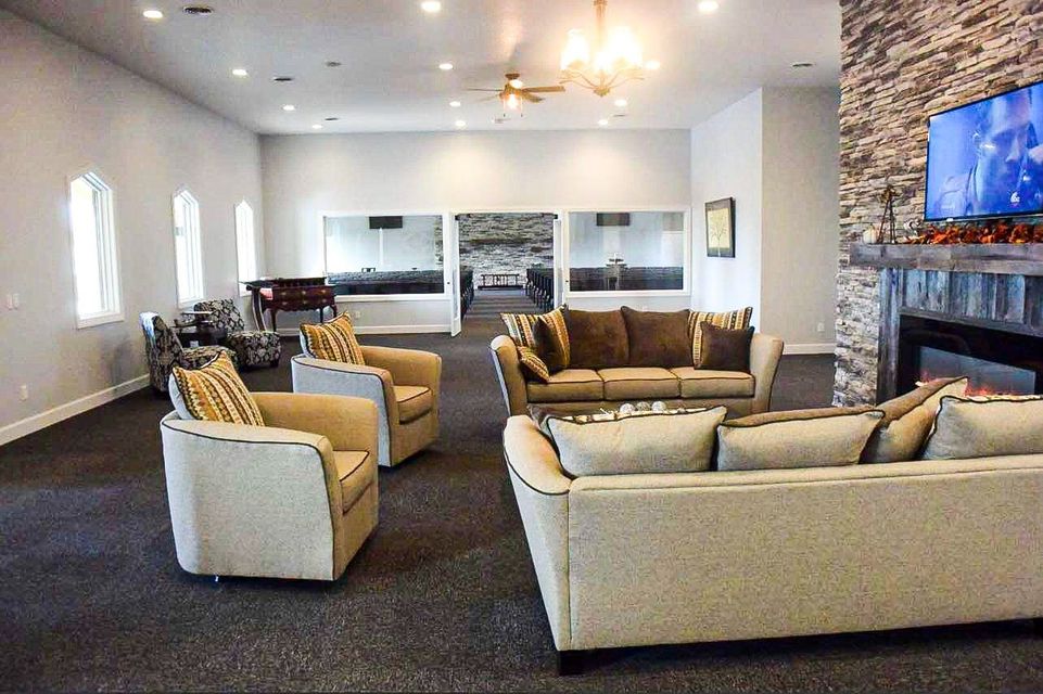 Spacious living room with beige sofas, armchairs, fireplace, and wall-mounted TV in a bright open layout