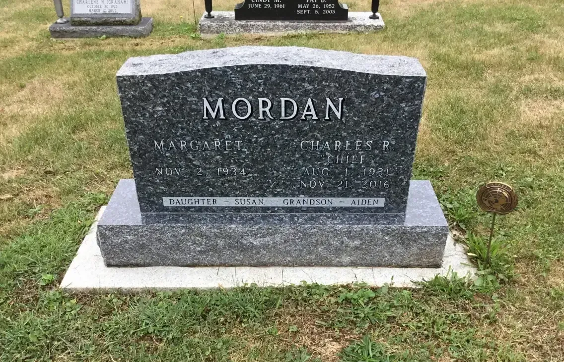 Gray granite gravestone marked “MORDAN” on a grassy cemetery plot