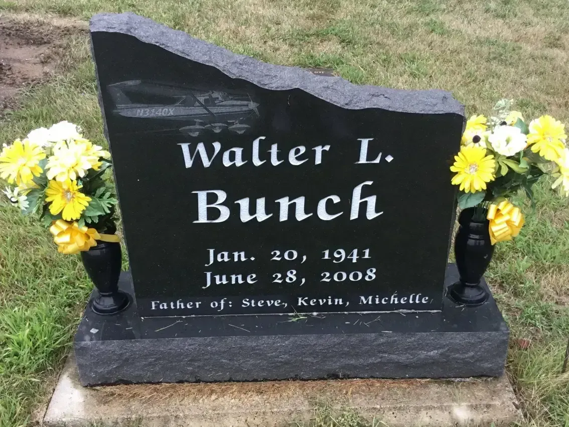Walter L. Bunce gravestone with yellow flowers on both sides, in a cemetery.
