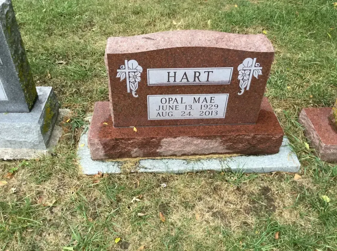 Red granite gravestone with the name Hart and floral engravings on a grassy cemetery plot.