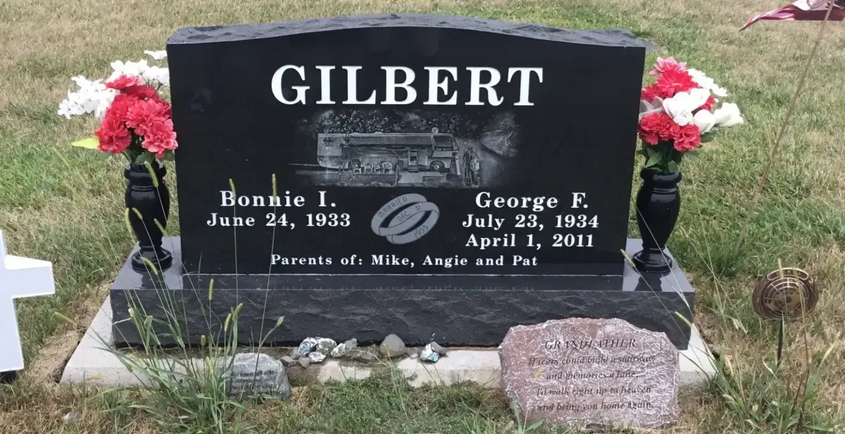 Black Gilbert gravestone with red flowers at a cemetery, marking Bonnie I. and George F.