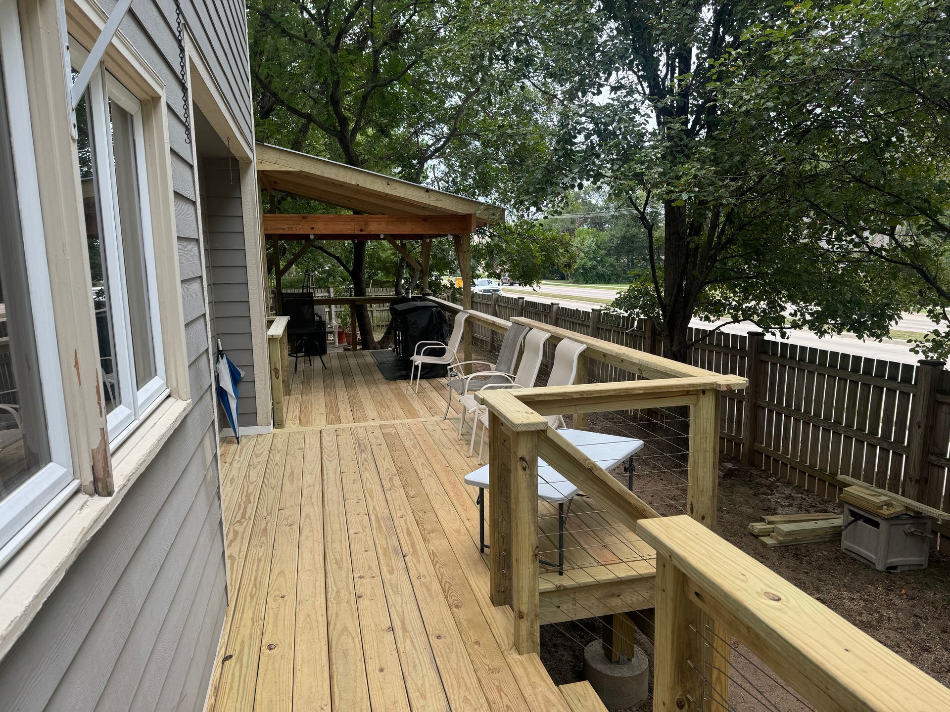 Wooden deck with railing, bench, and gazebo beside a house and fenced yard