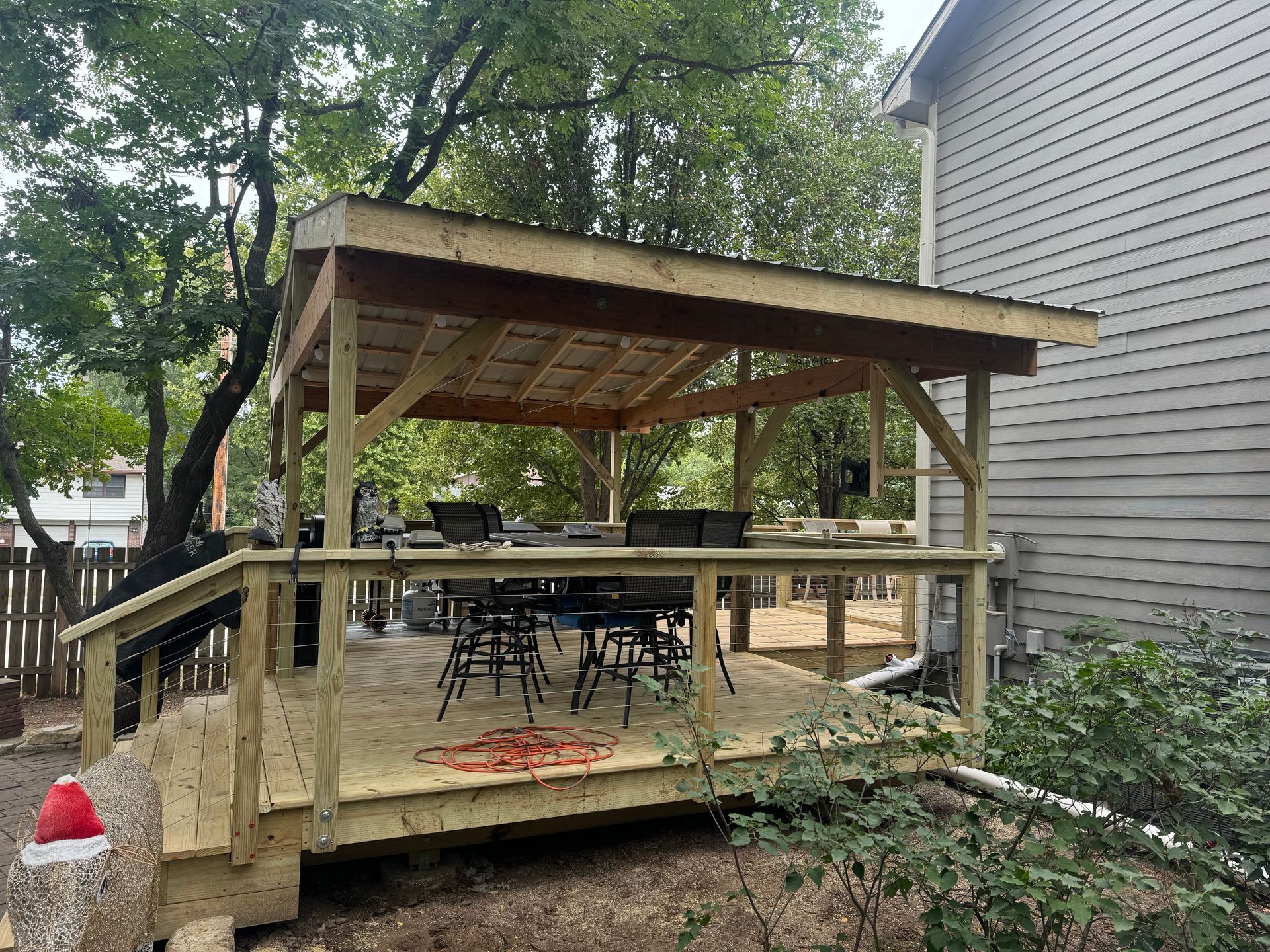 Wooden backyard deck with a covered seating area, picnic table, and ramp beside a house