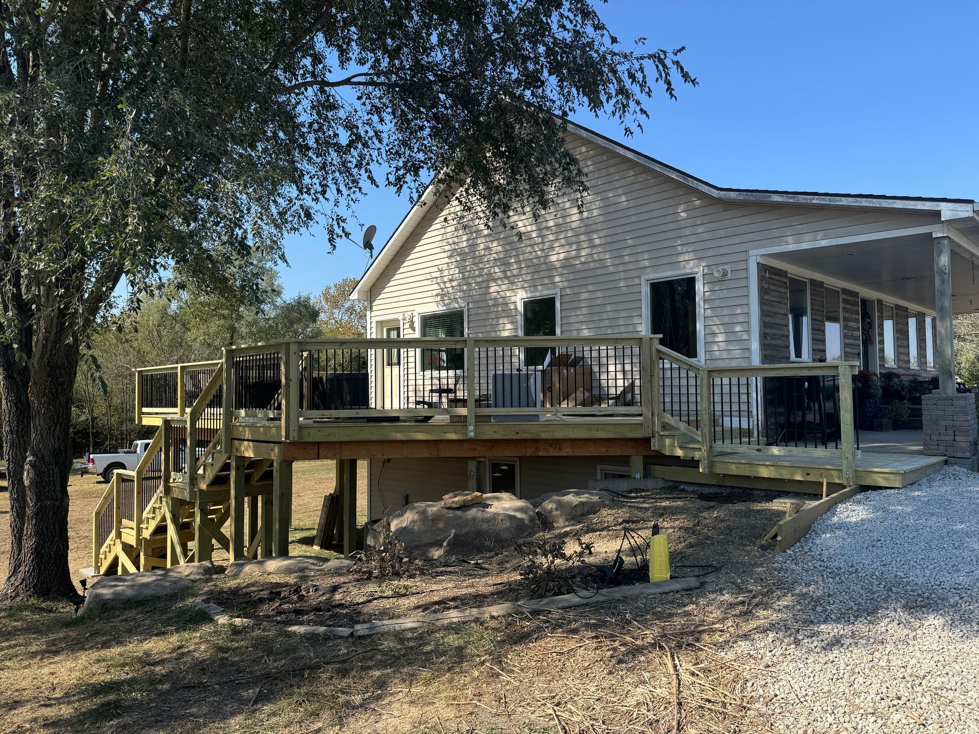 Stone house with a wooden deck and stairs on a wooded hillside under construction