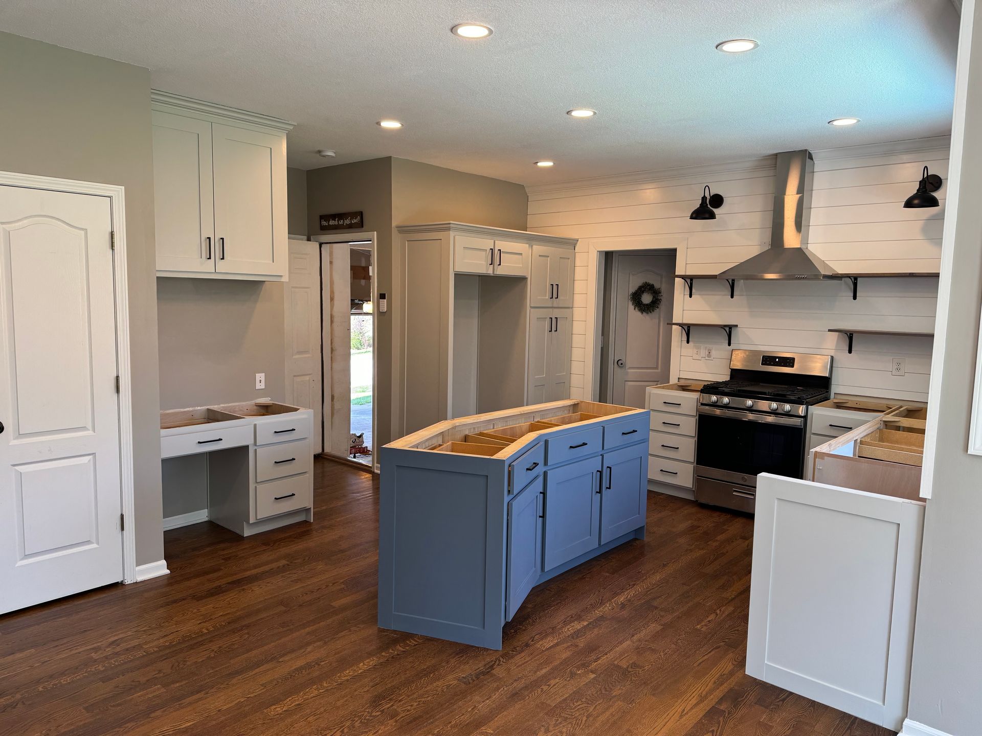 Modern kitchen with blue island, white cabinets, wood floors, and stainless steel appliances