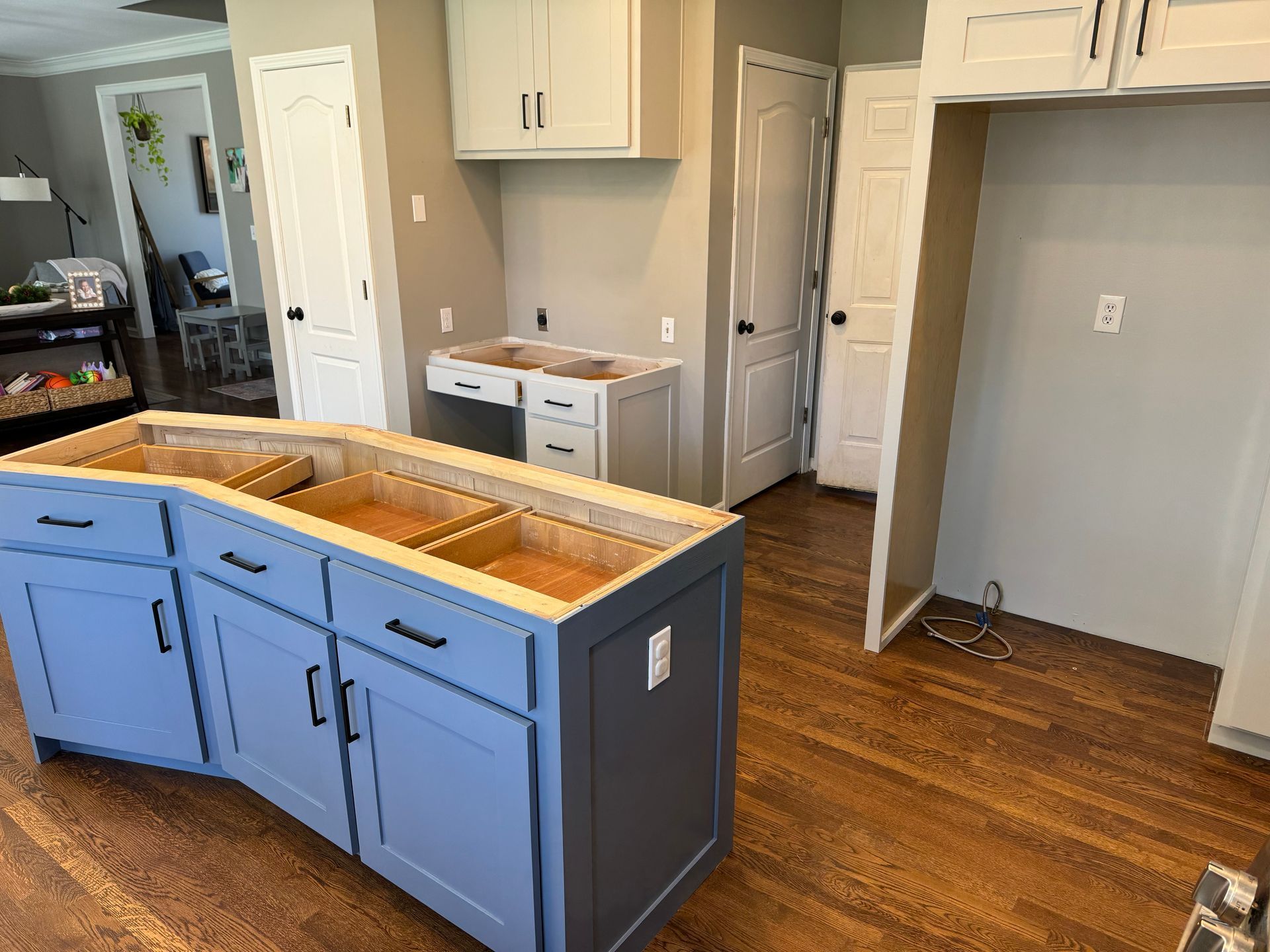Kitchen under renovation with blue island cabinets, wood floor, and white walls